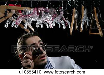 Stock Photography - young man standing 
beneath a row 
of hangers. fotosearch 
- search stock 
photos, pictures, 
images, and photo 
clipart