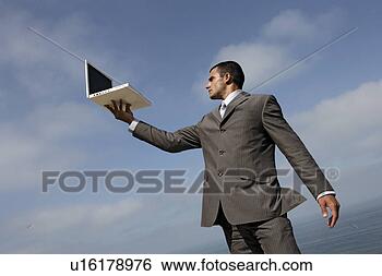Stock Photo - suited man holding 
a laptop. fotosearch 
- search stock 
photos, pictures, 
images, and photo 
clipart