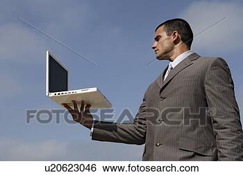 Stock Photo - view of a man 
holding a laptop. 
fotosearch - search 
stock photos, 
pictures, images, 
and photo clipart