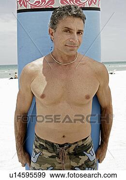 Stock Photograph - man standing in 
front of surfboard 
on beach. fotosearch 
- search stock 
photos, pictures, 
images, and photo 
clipart
