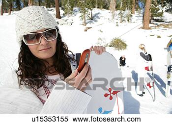 Stock Image - woman with a snowboarding 
looking at  a 
cell phone. fotosearch 
- search stock 
photos, pictures, 
images, and photo 
clipart