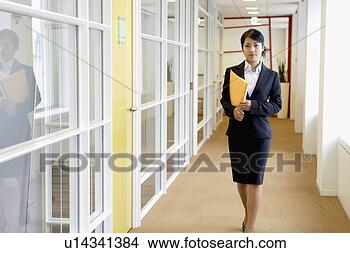 Stock Photo - a businesswoman 
holding a file 
walks along the 
passage of the 
office. fotosearch 
- search stock 
photos, pictures, 
images, and photo 
clipart