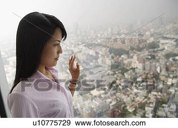 Stock Photograph - a formally dressed 
woman stands against 
the window lost 
in her. fotosearch 
- search stock 
photos, pictures, 
images, and photo 
clipart