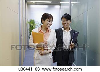 Stock Photo - two professional 
women holding 
files walks along 
the passage of 
the. fotosearch 
- search stock 
photos, pictures, 
images, and photo 
clipart