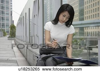 Stock Image - a woman holding 
a pen looks over 
the documents 
in a file. fotosearch 
- search stock 
photos, pictures, 
images, and photo 
clipart