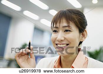 Stock Photo - a woman holding 
a pen smiles at 
someone. fotosearch 
- search stock 
photos, pictures, 
images, and photo 
clipart