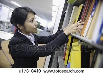 Stock Photography - a woman looks 
over the shelf 
containing various 
files. fotosearch 
- search stock 
photos, pictures, 
images, and photo 
clipart