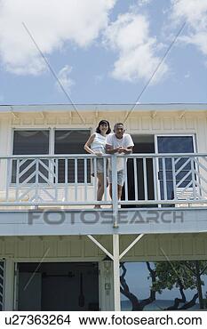 Stock Photo - low angle view 
of a couple on 
balcony. fotosearch 
- search stock 
photos, pictures, 
images, and photo 
clipart