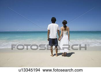 Stock Photo - rear view of a 
young couple holding 
hands at beach. 
fotosearch - search 
stock photos, 
pictures, images, 
and photo clipart