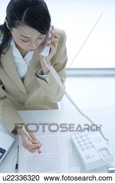 Stock Photography - a young woman 
talking over phone 
in office. fotosearch 
- search stock 
photos, pictures, 
images, and photo 
clipart
