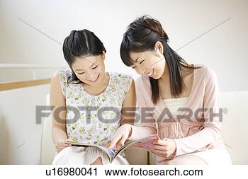 Stock Photography - two young women 
reading magazine 
together. fotosearch 
- search stock 
photos, pictures, 
images, and photo 
clipart