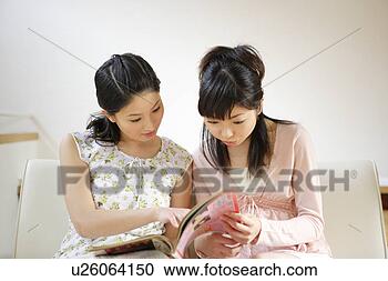 Stock Photography - two young women 
reading magazine 
together. fotosearch 
- search stock 
photos, pictures, 
images, and photo 
clipart