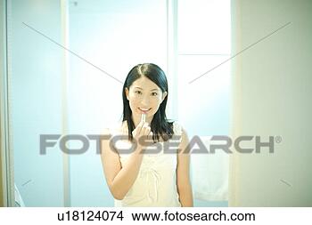Stock Photo - young woman applying 
lipstick. fotosearch 
- search stock 
photos, pictures, 
images, and photo 
clipart