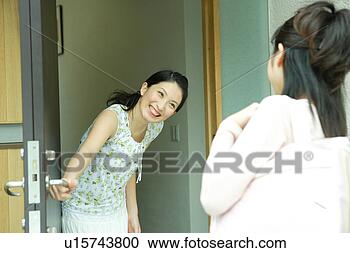 Stock Photography - young woman greeting 
her friend at 
entrance. fotosearch 
- search stock 
photos, pictures, 
images, and photo 
clipart