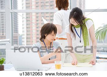 Stock Photo - two young women 
looking at notebook 
and young man 
standing behind. 
fotosearch - search 
stock photos, 
pictures, images, 
and photo clipart