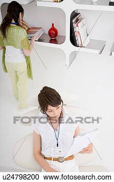 Stock Photography - a young woman 
reading document 
with a young woman 
standing behind. 
fotosearch - search 
stock photos, 
pictures, images, 
and photo clipart