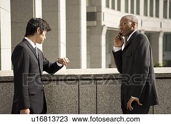 Stock Photo - two businessmen, 
one using mobile 
phone. fotosearch 
- search stock 
photos, pictures, 
images, and photo 
clipart