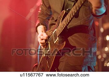 Picture - young man playing 
electric guitar 
on stage. fotosearch 
- search stock 
photos, pictures, 
images, and photo 
clipart