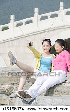Stock Photo - young women taking 
photos, sitting 
on stairs. fotosearch 
- search stock 
photos, pictures, 
images, and photo 
clipart