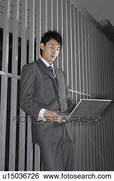 Stock Photo - business man holding 
laptop in front 
of bars. fotosearch 
- search stock 
photos, pictures, 
images, and photo 
clipart