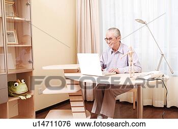 Stock Photo - elderly man playing 
with laptop at 
desk. fotosearch 
- search stock 
photos, pictures, 
images, and photo 
clipart
