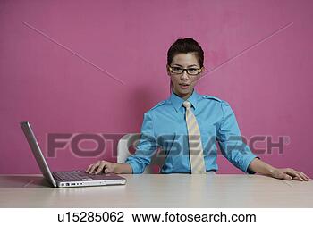 Stock Photo - office woman sitting 
at desk with a 
laptop. fotosearch 
- search stock 
photos, pictures, 
images, and photo 
clipart