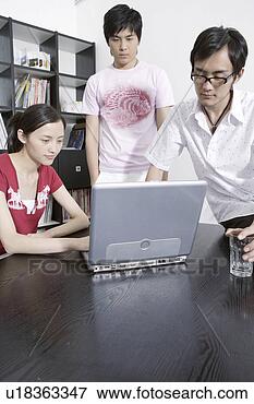 Picture - two young men 
and woman watching 
on screen of laptop. 
fotosearch - search 
stock photos, 
pictures, images, 
and photo clipart