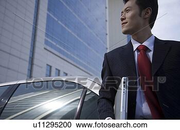 Stock Photography - young man holding 
a laptop in front 
of car. fotosearch 
- search stock 
photos, pictures, 
images, and photo 
clipart