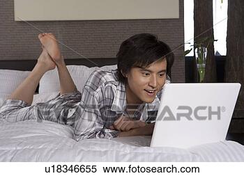 Stock Image - young man lying 
in bed with laptop. 
fotosearch - search 
stock photos, 
pictures, images, 
and photo clipart