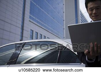 Stock Photography - young man playing 
with laptop in 
front of car. 
fotosearch - search 
stock photos, 
pictures, images, 
and photo clipart