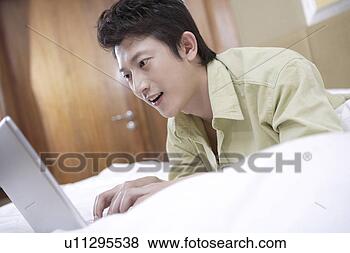 Stock Photo - young man playing 
with laptop in 
bed. fotosearch 
- search stock 
photos, pictures, 
images, and photo 
clipart
