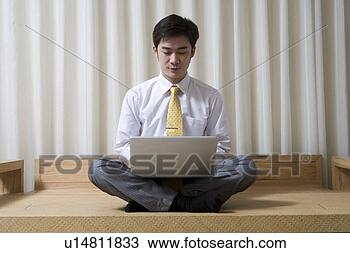 Stock Photo - young man sitting, 
playing with laptop. 
fotosearch - search 
stock photos, 
pictures, images, 
and photo clipart