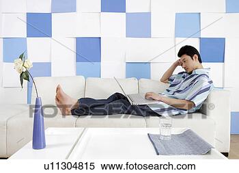 Stock Image - young man using 
laptop in sofa. 
fotosearch - search 
stock photos, 
pictures, images, 
and photo clipart