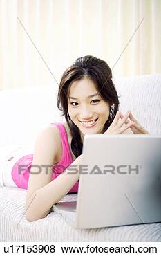 Stock Photo - young woman looking 
at laptop in sofa. 
fotosearch - search 
stock photos, 
pictures, images, 
and photo clipart