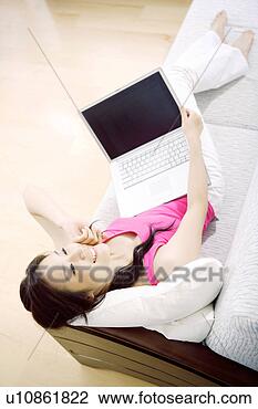 Stock Photo - young woman lying 
in sofa with laptop. 
fotosearch - search 
stock photos, 
pictures, images, 
and photo clipart