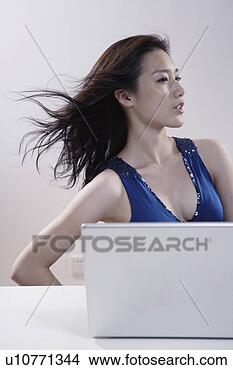 Stock Photo - young woman sitting 
at desk with laptop. 
fotosearch - search 
stock photos, 
pictures, images, 
and photo clipart
