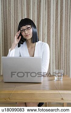 Stock Photo - young woman sitting 
behind laptop 
at desk. fotosearch 
- search stock 
photos, pictures, 
images, and photo 
clipart