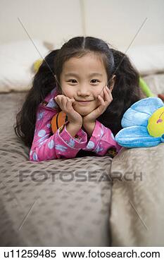 Stock Image - girl lying with 
doll in bed. fotosearch 
- search stock 
photos, pictures, 
images, and photo 
clipart