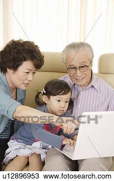 Stock Photo - senior couple 
and granddaughter 
playing with laptop 
in sofa. fotosearch 
- search stock 
photos, pictures, 
images, and photo 
clipart