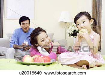 Stock Photography - young family eating 
fruit at the sitting 
room. fotosearch 
- search stock 
photos, pictures, 
images, and photo 
clipart