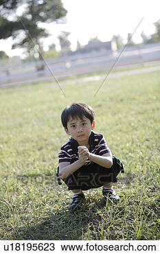 Stock Photo - boy crouching 
on lawn. fotosearch 
- search stock 
photos, pictures, 
images, and photo 
clipart
