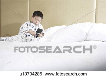 Stock Photo - boy playing with 
video game in 
bed. fotosearch 
- search stock 
photos, pictures, 
images, and photo 
clipart