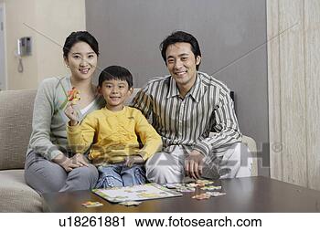 Stock Photography - family sitting 
in sofa and smiling 
into camera. fotosearch 
- search stock 
photos, pictures, 
images, and photo 
clipart