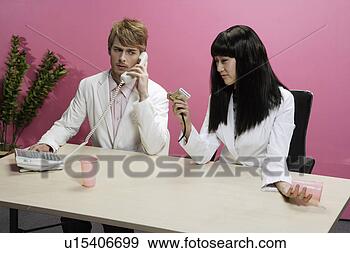 Stock Photograph - occidental man 
and asian woman 
phoning at desk. 
fotosearch - search 
stock photos, 
pictures, images, 
and photo clipart
