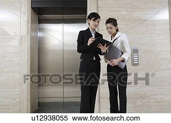 Stock Image - two office women 
looking at files 
near lift. fotosearch 
- search stock 
photos, pictures, 
images, and photo 
clipart