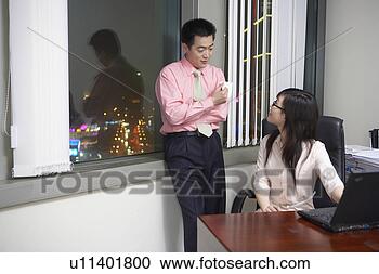 Stock Photography - young man chatting 
with young woman 
at office. fotosearch 
- search stock 
photos, pictures, 
images, and photo 
clipart