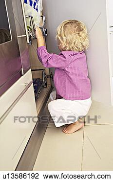 Stock Photo - little girl in 
kitchen, in front 
of a cabinet, 
indoors. fotosearch 
- search stock 
photos, pictures, 
images, and photo 
clipart