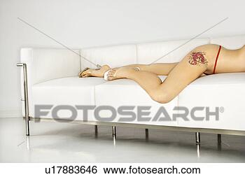 Stock Photo - portrait of attractive 
 caucasian young 
woman lying on 
sofa in thong. 
fotosearch - search 
stock photos, 
pictures, images, 
and photo clipart