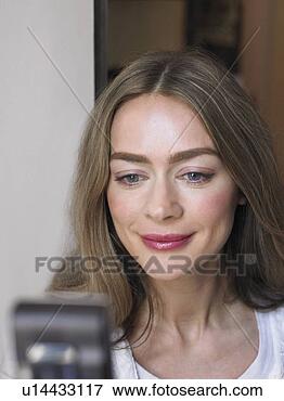 Picture - woman looking 
at mobile phone, 
smiling, close-up. 
fotosearch - search 
stock photos, 
pictures, images, 
and photo clipart