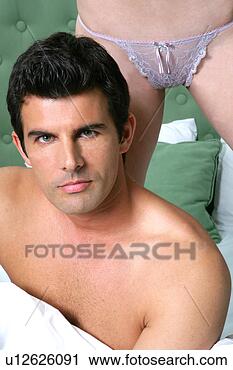 Stock Photography - young man in bed 
with woman in 
underwear behind. 
fotosearch - search 
stock photos, 
pictures, images, 
and photo clipart